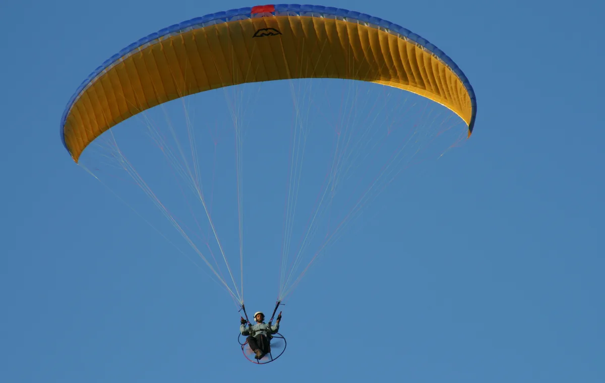 Mavi gökyüzünde uçan paramotor pilotu